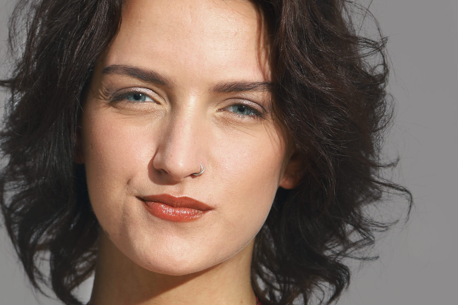 Eine geschminkte Frau mit leicht zweifelndem Gesichtsausdruck.